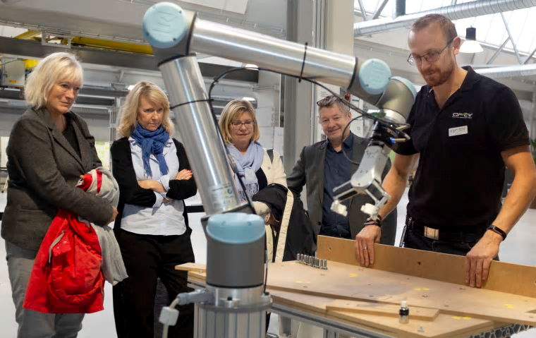 Högskolan i Skövdes styrelse besöker innovationsmiljön ASSAR. Styrelsens ordförande Kerstin Norén, ledamoten Pia Kronqvist, prorektor Lena Mårtensson och rektor Lars Niklasson tittar medan Niklas Land beskriver hur en kollaborativ robot arbetar.