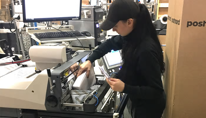 Fatima på Almroths laddar Autobagmaskinen med träningskläder.