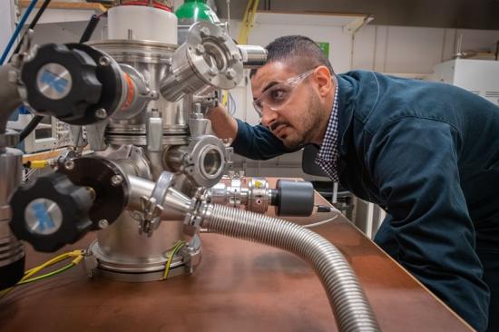 Hama Nadhom justerar gasflödet till vakuumkammaren där LiU-forskarna studerar hur plasmaelektroner kan användas för att skapa tunna metallfilmer.