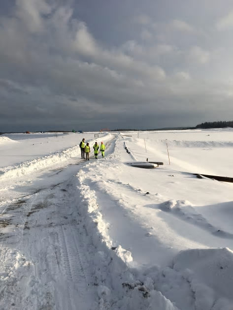 Delar av projektgruppen inspekterar Zinkgruvans sandmagasin som med hjälp av grävmaskinen i bakgrunden skall täckas med grönlutslam från Aspa Bruk vid ett pilotförsök i vår.